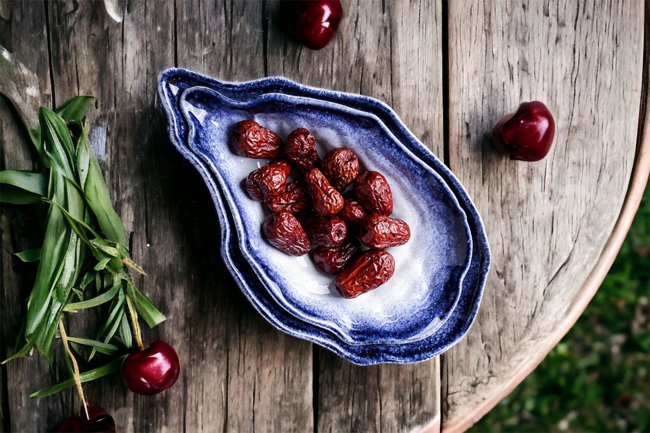 home decor collection with elvated sustainable home goods. image depicts an oyster shaped serving platter with olives on a rustic table